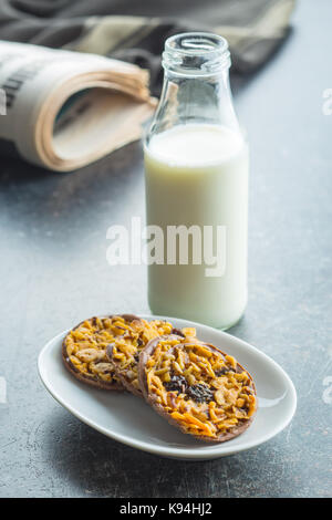 I biscotti al cioccolato con noci e uvetta. cookie e bottiglia di latte. Foto Stock