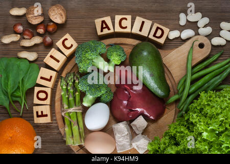 Fonti naturali di acido folico come fegato, asparagi, broccoli, uova, insalata di avocado, lievito, dadi, spinaci, arancione e fagioli Foto Stock