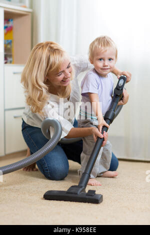 La famiglia felice pulisce la camera con la Hoover Foto Stock