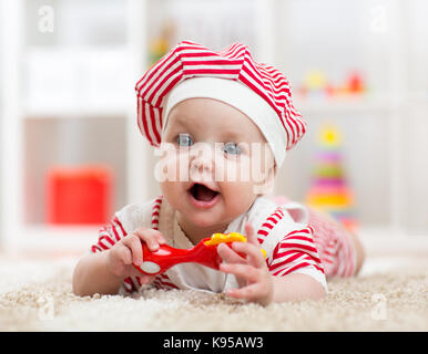 Baby girl sdraiato sul pavimento e gioca con il giocattolo indoor Foto Stock