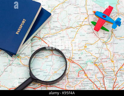Aeroplano in miniatura, passaporto e lente di ingrandimento sulla mappa , viaggi in tutto il mondo, sfondo Foto Stock