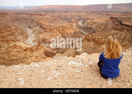 Ragazza bionda guardando il Fish River Canyon in Namibia dal punto di vista vicino a hobas. Foto Stock