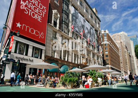 La gente camminare & relax presso il centro commerciale pedonale accanto al lato ingresso del magazzino Macy's a 34th Street e Broadway nel centro di Manhattan. Foto Stock