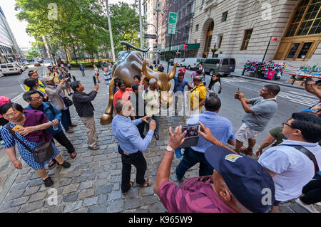 La carica Bull statua e la ragazza impavida statua circondata da turisti nel quartiere finanziario, vicino alla Borsa di New York a Manhattan, Foto Stock