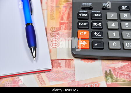 Calcolatrice nero e blu penna con notebook giacente sul russo cinque-millesimo banconote. business still life Foto Stock