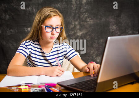 Annoiato ragazza adolescente facendo compiti a casa Foto Stock