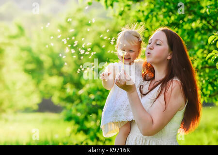 Donna e bambino che soffia su un dente di leone Foto Stock