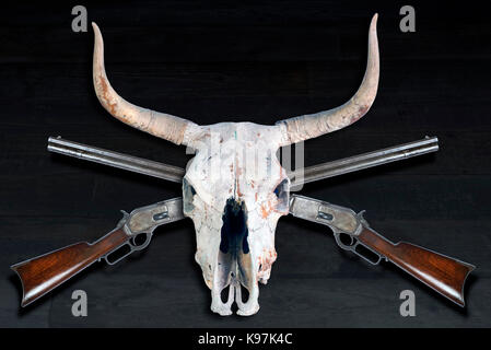 Antique cowboy azione di leva fucile e teschi di mucca. Foto Stock