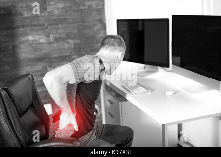 L uomo che soffre di mal di schiena mentre è seduto alla scrivania in ufficio Foto Stock