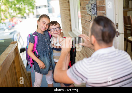 Bambino caucasian esce di casa per il suo primo giorno di scuola materna Foto Stock