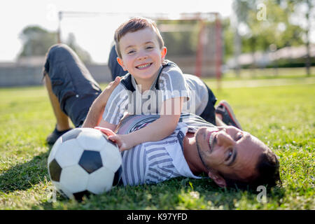 Uomo con bambino giocando a calcio sul campo Foto Stock