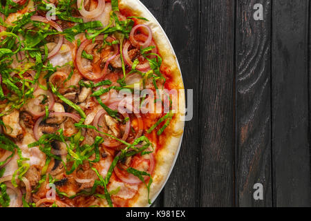 Vista superiore della gustosa pizza con salsiccia e scalogno scuro su sfondo di legno Foto Stock