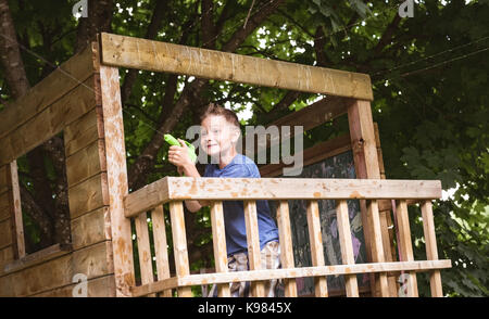 Carino ragazzo giocando con pistola giocattolo in parco giochi Foto Stock
