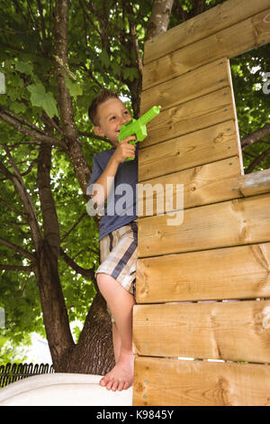 Carino ragazzo giocando con pistola giocattolo in parco giochi Foto Stock