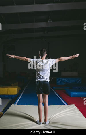 Vista posteriore del ginnasta maschio pronto per eseguire esercizi di ginnastica in palestra Foto Stock