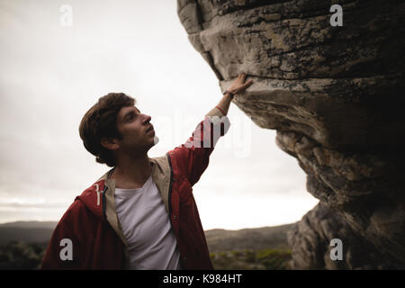 Uomo in piedi sotto la scogliera in una giornata di sole Foto Stock