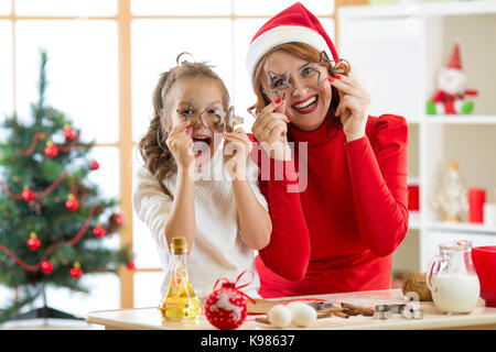 La famiglia felice la madre e il bambino sono un modo divertente di preparare la pasta. la donna e la figlia cuocere biscotti di Natale in festival sala decorata Foto Stock