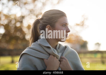 Considerato giovane donna avvolta in una coperta permanente al park Foto Stock