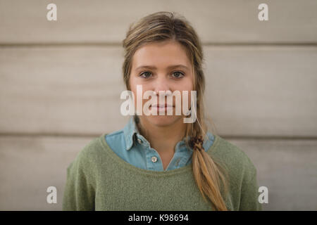 Ritratto di fiducioso giovane donna in piedi contro la parete Foto Stock