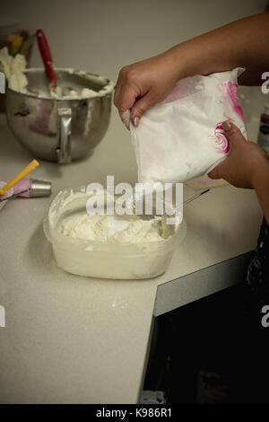 Donna versando la farina in un recipiente in cucina a casa Foto Stock