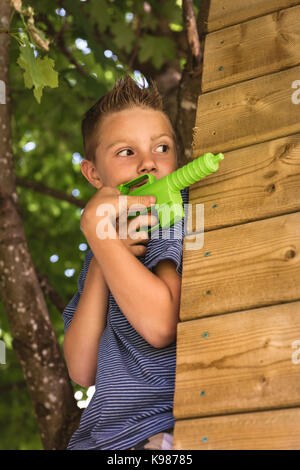 Carino ragazzo giocando con pistola giocattolo in parco giochi Foto Stock