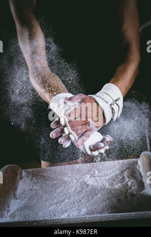 Sezione centrale del ginnasta maschio strofinando le mani con polvere di gesso Foto Stock