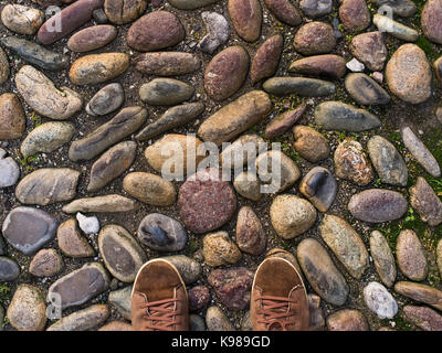 Piedi in marrone sneakers sul vecchio centro medievale pavimentazione di pietra. Foto Stock