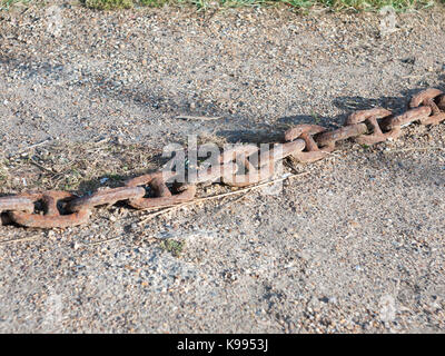 Il vecchio metallo arrugginito catena attraverso la pietra pavimento esterno; Inghilterra; essex Foto Stock