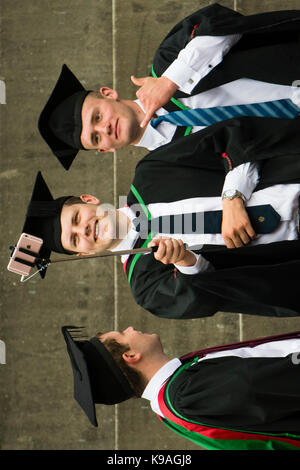 Istruzione superiore nel Regno Unito: Aberystwyth gli studenti universitari di prendere una fotografia selfie indossando accademici tradizionali abiti e schede di mortaio sul loro giorno di graduazione, luglio 2917 Foto Stock