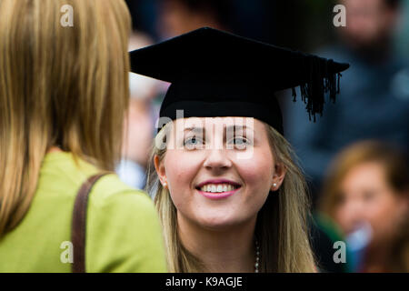 Istruzione superiore nel Regno Unito: un felice smiloing donna femmina aberystwyth studente universitario che indossa il suo tradizionale abito di accademici e di mortaio board sul suo giorno di graduazione, luglio 2017 Foto Stock