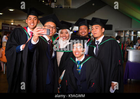 Istruzione superiore nel Regno Unito: un gruppo di stranieri asiatici oltremare Aberystwyth studenti universitari indossando accademici tradizionali abiti e schede di mortaio di prendere una fotografia selfie sul loro giorno di graduazione, Luglio 2017 Foto Stock