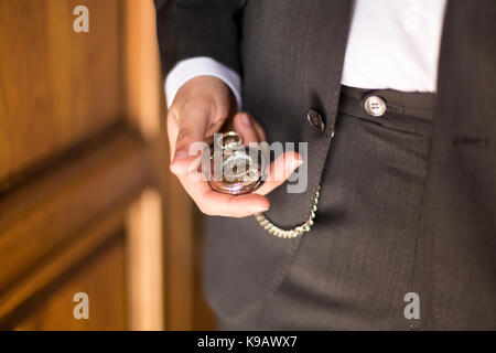 Lo sposo guardando il tempo nel suo orologio da tasca Foto Stock