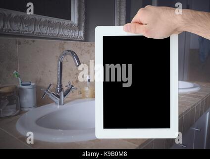Composito Digitale della mano che tiene tablet a casa bagno Foto Stock