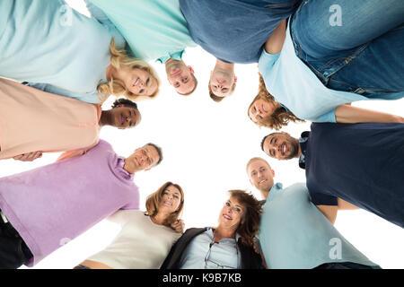 Direttamente sotto il ritratto di attività creativa di persone in piedi in huddle contro uno sfondo bianco Foto Stock