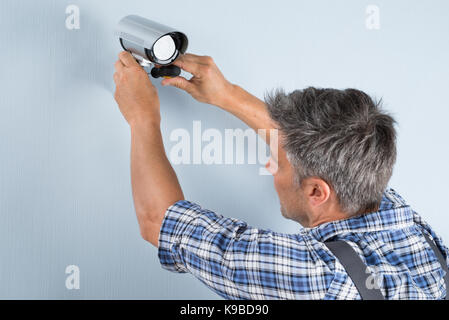 Close-up di un tecnico regolazione della telecamera TVCC sulla parete Foto Stock