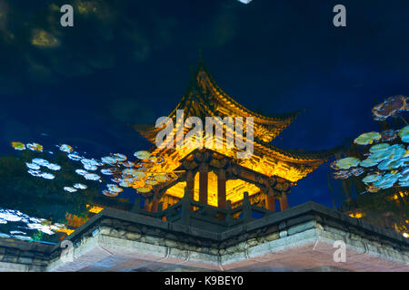 Uno stile cinese pagoda illuminato artisitically riflessa in acqua di stagno di notte nella città vecchia di Lijiang, Cina Foto Stock