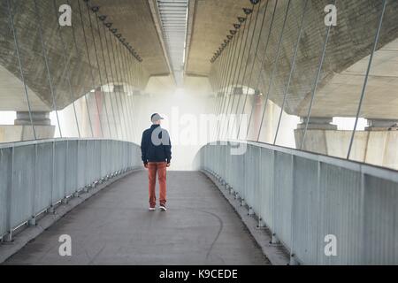 L'uomo sulla passerella sotto il ponte dell'autostrada nella misteriosa nebbia di mattina. Praga, Repubblica ceca Foto Stock