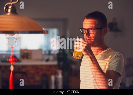 Mattina tempo a casa. pensieroso uomo di bere succo di frutta in cucina. Foto Stock
