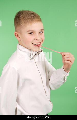 Ragazzo giovane stiramento da gomma da masticare che egli porta nella sua bocca isolati su sfondo verde Foto Stock