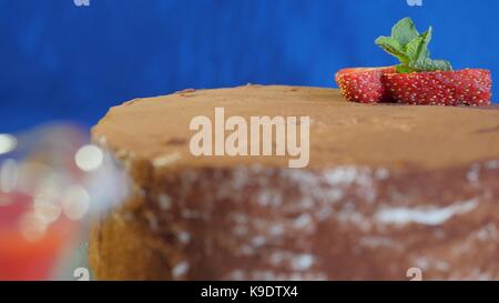 Close-up di fatti in casa torta al cioccolato con fragole su sfondo blu scuro. dessert cioccolato. fresca torta di fragole con topping di cioccolato su un tavolo Foto Stock