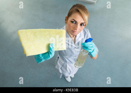 Angolo di alta vista della cameriera femmina in uniforme di strofinamento con un panno Foto Stock