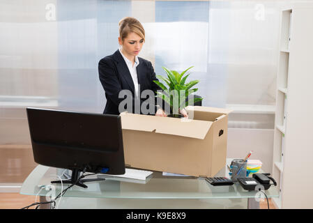 Infelice imprenditrice imballaggio gli effetti personali nella casella Foto Stock