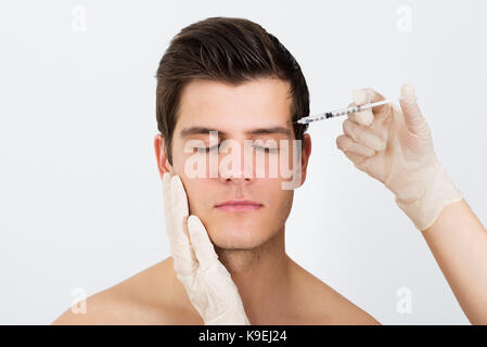 Close-up di persona le mani siringa di iniezione con Botox per il trattamento del viso Foto Stock