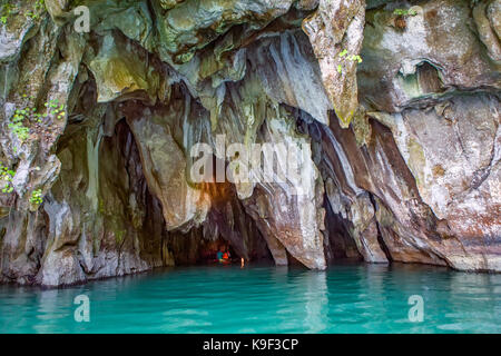 Una barca piena di turisti entrare nella bocca di una grotta sul fiume Cabayugan per visitare il famoso Puerto Princesa Fiume Sotterraneo Parco Nazionale, un Foto Stock