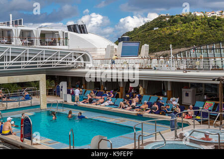 I passeggeri a prendere il sole e nuotare in a bordo piscina su una crociera nei Caraibi Liner ancorato in Philipsburg, Sint Maarten. Foto Stock