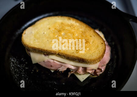 Una padella in ghisa e pasta acida pane è una combinazione di un grande panino. golden brown pane, prosciutto della Foresta Nera e fuso il formaggio svizzero. Foto Stock