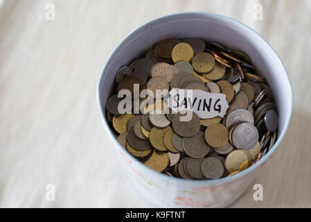 Monete in stagno con note scritte mediante la parola 'salvataggio'. concetto di risparmio finanziario e concetto. malaysia valuta Foto Stock