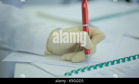 Sezione mediana del medico iscritto su carta in clinica. close up il paziente e il medico prendendo appunti. medico iscritto una prescrizione. fisioterapista iscritto negli appunti in clinica. medico donna scrivendo una prescrizione. uno scienziato prende appunti in un notebook. Scienza e medicina Foto Stock