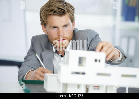 Felice giovane architetto maschio la creazione di un modello di casa Foto Stock