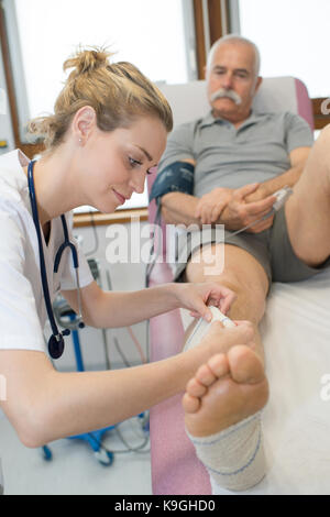 Bella medico del bendaggio senior mans gamba ferita Foto Stock